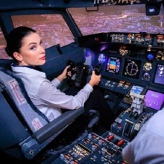 Пилот управляет самолётом в кабине во время ночного полёта над городом