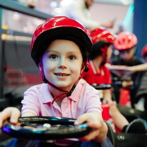 Дети катаются на картингах в развлекательном центре в вечернее время Дети катаются на картингах в развлекательном центре в вечернее время