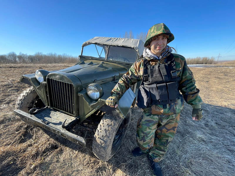 Военный солдат рядом с автомобилем на открытом поле в ясный день весной